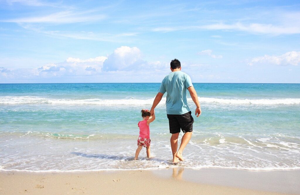 Vater hat Tochter an der Hand Strand Mitfühlende und freundliche Kinder erziehen