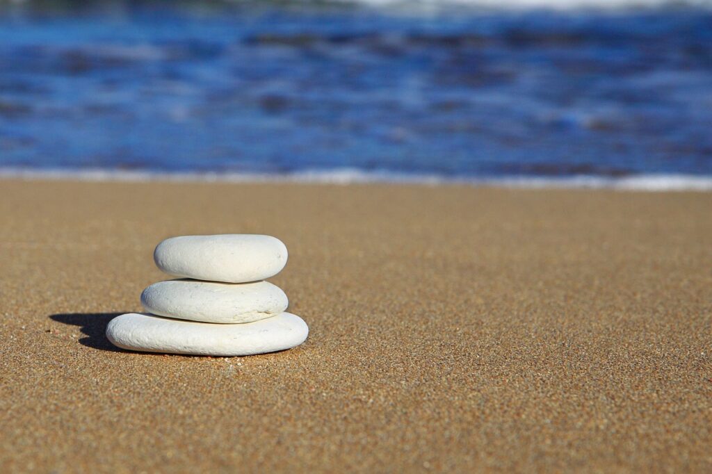 Steine am Strand gestapelt Die Bedeutung von Chakra-Steinen und Yoni-Eiern für dein Wohlbefinden